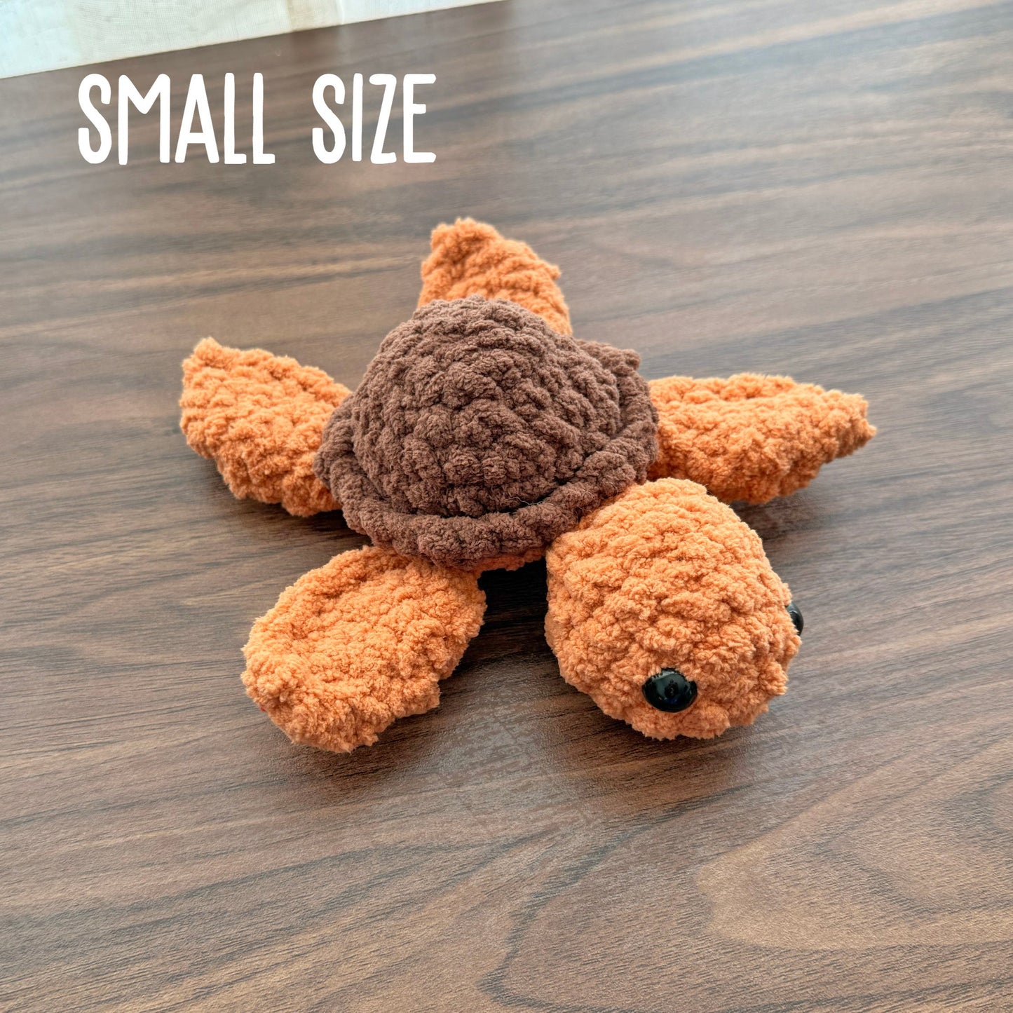 Small turtle plush with a brown shell and burnt orange body 